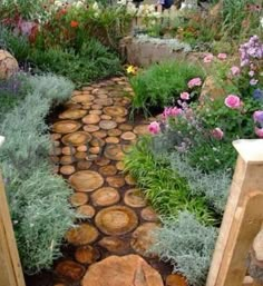 a pathway made out of logs with flowers in the background