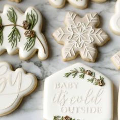 decorated cookies with the words baby it's cold outside and pine cones on them