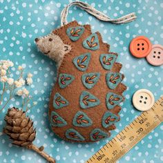 a stuffed hedge sitting next to a pine cone and some buttons on a blue polka dot table cloth