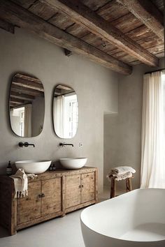 a bathroom with two sinks, mirrors and a tub in the middle of the room