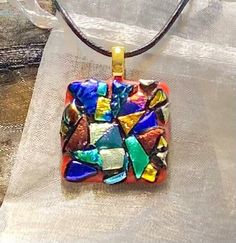 A unique, kiln fused, dichroic glass pendant, custom designed for you, arranged capped with a patchwork of bold,bright and shiny multi-colored textured shapes on a red base and has a black leather cord necklace & 1.5 inch extension chain and nickel-free, silver-plated clasp.  A fashionable accessory & stylish as a chic & modern, sparkling glass necklace.  Dress up blue jeans, relax in loungewear or accent your evening attire.  Created & handcrafted in a home workshop. Select an original mosaic art glass pendant to add to your jewelry collection or as a gift for a loved one, friend, nurse, teacher, etc. An organza gift bag is included with your order. Thanks for visiting. Aloha! designworksbyfaye.etsy.com www.etsy.com/shop/DesignWorksByFaye Multicolor Recycled Glass Jewelry As A Gift, Multicolor Recycled Glass Jewelry For Gifts, Artistic Glass Round Pendant Necklaces, Artistic Glass Necklace With Round Pendant, Artistic Glass Round Pendant Necklace, Handmade Round Necklace With Eco-friendly Glass, Handmade Round Recycled Glass Necklace, Multicolor Recycled Glass Necklaces For Gifts, Multicolor Recycled Glass Necklace As Gift