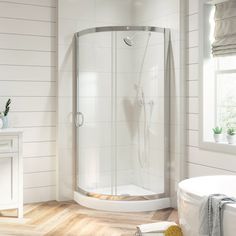 a bathroom with white walls and wooden flooring, including a corner shower stall next to a bathtub