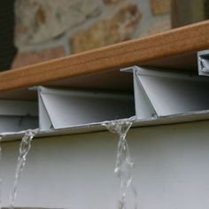 water gushing from the gutter in front of a window