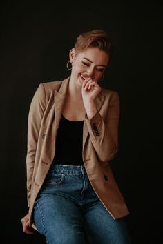 a woman sitting on a chair with her hand to her face and smiling at the camera