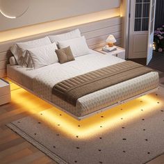 a large bed sitting on top of a wooden floor next to a night stand with lights