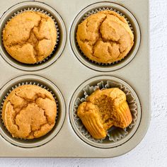 four muffins in a cupcake tin on a white table top with one missing