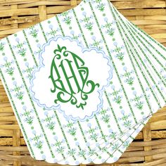 four monogrammed napkins on top of each other in front of a basket