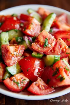 a white bowl filled with cucumber and tomato salad