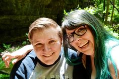 two people with green hair and glasses posing for a photo in front of some trees