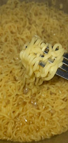 a fork full of noodles being cooked in a pot