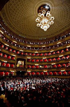 an auditorium filled with people and chandeliers