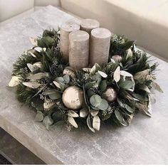 some candles are sitting on a table with greenery