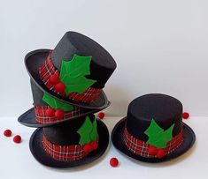 two black hats with holly leaves on them and red berries around the brimmed hat