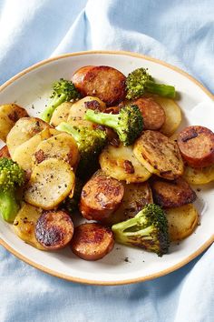 a white plate topped with potatoes and broccoli on top of a blue cloth