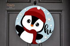 a door hanger with a penguin wearing a red hat and scarf on it's face