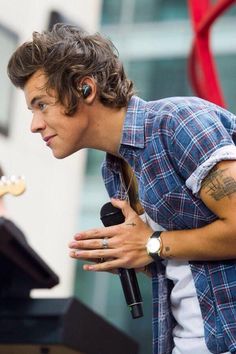 a young man with ear buds on his ears holding a microphone in front of him