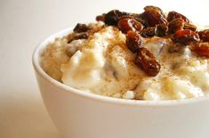 a white bowl filled with oatmeal topped with raisins and nuts