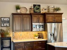 a kitchen with wooden cabinets and stainless steel appliances in the center is decorated with potted plants