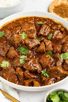 a white bowl filled with meat and garnished with cilantro