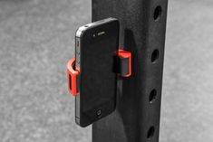 a cell phone is attached to a black pole with red clips on it and an orange clip in the middle