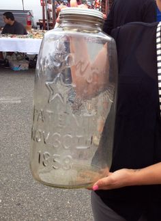 a woman holding a large jar with writing on it