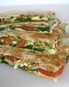 three quesadillas stacked on top of each other with tomatoes and green peppers