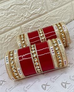 two red and gold bangles sitting on top of a white table next to a wall