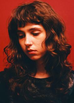 a close up of a person with long hair and eyes closed against a red background