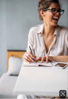 a woman is smiling and writing on a notepad