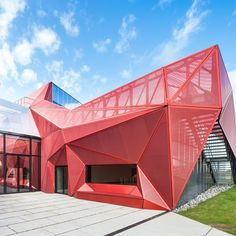 a red building that is on the side of a road with lots of windows and grass