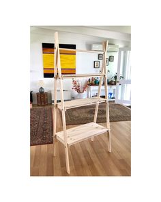 a wooden shelf sitting on top of a hard wood floor in a living room next to a rug