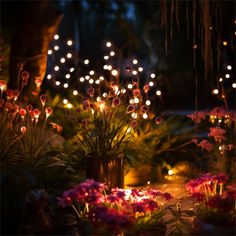 some lights that are on in the ground near flowers and plants with pink flowers around them