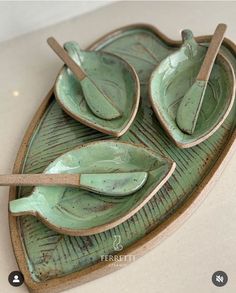 three green leaf shaped dishes sitting on top of a white counter