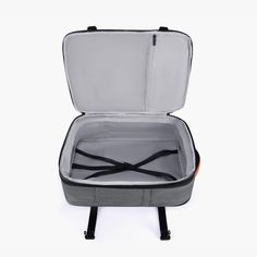 an open suitcase sitting on top of a white floor next to a black handle and seat