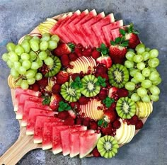 a platter filled with watermelon, kiwis and grapes on top of each other