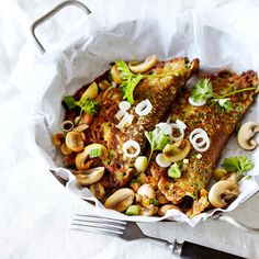 two fish fillets with mushrooms and parsley in a basket on a white tablecloth