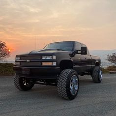 a large black truck parked on top of a gravel road