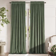 a living room with green curtains and a white chair in front of the door that is open