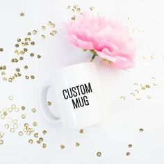 a pink flower sitting on top of a white coffee mug next to gold confetti