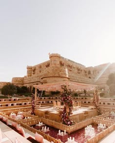 an outdoor wedding setup in front of a castle like building with flowers and candles on it