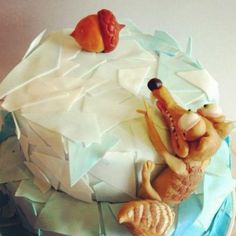 there is a cake decorated with animals on it's side and frosting in the shape of an iceberg