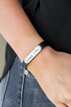 A silver plate engraved with the inspirational phrase "love life" is studded in place along a skinny strip of black leather. Brushed in a shiny finish, the dainty band wraps around the wrist for a simple seasonal style. Features an adjustable snap closure.

Sold as one individual bracelet. 

This Fan Favorite is back in the spotlight at the request of our 2021 Life of the Party member with Black Diamond Access, Robert F. Paparazzi Jewelry Images, Snap Words, Dainty Band, Diamond Life, Word Bracelet, Snap Bracelets, Paparazzi Accessories, Black Bracelets, Paparazzi Jewelry