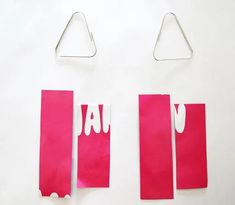 three pieces of pink paper with white letters on them and one piece cut out to look like a pair of scissors