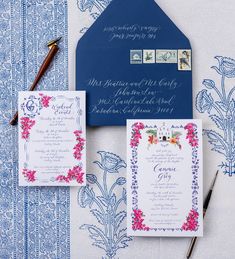 the wedding stationery is laid out on a blue and white tablecloth with pink flowers