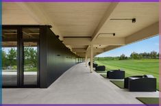 an empty walkway between two buildings with glass doors on each side and green grass in the background