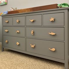 a gray dresser with gold knobs in a child's room