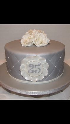 a silver cake with white flowers on top and the number twenty five in the middle