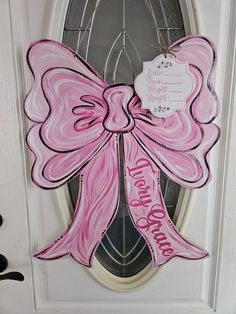 a pink door hanger with a large bow on it's front door that says welcome home