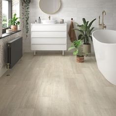 a bathroom with white walls and wood flooring next to a bathtub in the corner