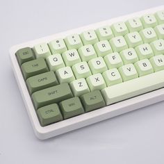 a green and white computer keyboard on a gray surface with the keys highlighted in black